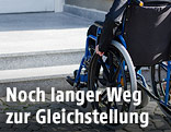 Mann in Rollstul vor Stufen