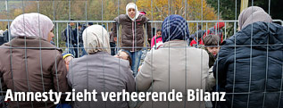 Fl&uuml;chtlinge hinter einem Zaun