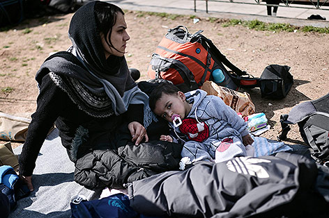 © APA/AFP/Louisa Gouliamaki Frau sitzt mit Kind auf dem Boden