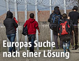 Flüchtlinge gehen an einem zaun entlang