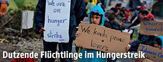 Flüchtlinge in Idomeni mit beschriebenen Kartonschildern