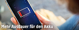 Frau hält Handy mit leerem Akku in der Hand