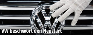Mitarbeiter ber&uuml;hrt das Logo eines VW-Autos