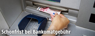 Frau behebt Geld an einem Bankomat