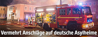 Feuerwehreinsatzkräfte löschen einen Brand in einer Asylunterkunft
