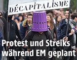 Demonstrant mit Kübel am Kopf und Transparent in der Hand