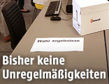 Tisch mit einem Zettel mit der Aufschrift "Wahlergebnisse"