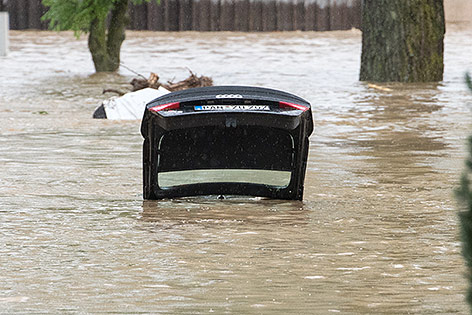 © APA/dpa/Armin Weigel Die offene Kofferraumklappe eines Fahrzeuges ragt aus dem Hochwasser