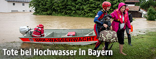 Rettungskräfte der Wasserwacht evakuieren eine Frau mit einem Boot