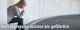 Verzweifelte Jugendliche sitzt in einer Garagenauffahrt, den Kopf in die Hände gestützt