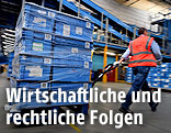 Ein Arbeiter zieht eine Palette mit Kisten