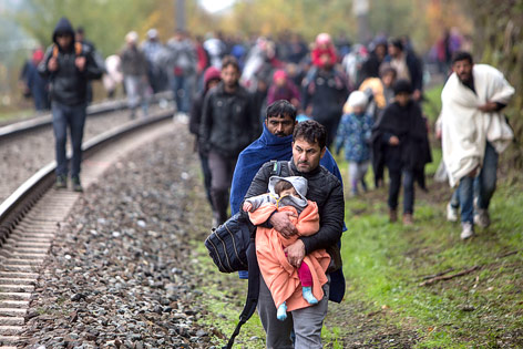 © APA/AFP/Vladimir Simicek Flüchtlinge gehen auf einer Bahntrasse in der Nähe von Spielfeld