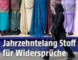 Frau in Burka geht an einem Gewandgesch&auml;ft mit langen Kleidern vorbei