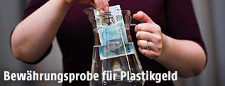 Eine neue F&uuml;nf-Pfund-Banknote aus Plastik wird in einen Krug mit Wasser getaucht
