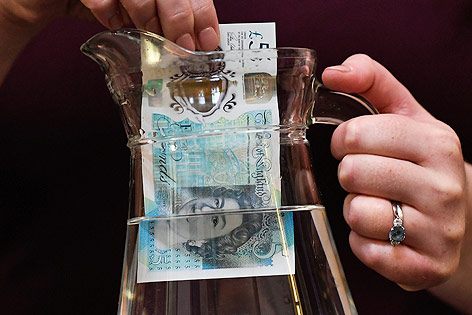 Eine neue Fünf-Pfund-Banknote aus Plastik wird in einen Krug mit Wasser getaucht