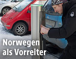Mann an einer Ladestation für E-Autos in Oslo, Norwegen