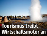 Touristen fotografieren einen Geysir in Island
