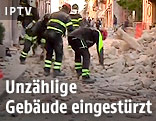 Feuerwehrmänner vor einem eingestürztem Haus