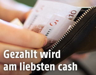 frau nimmt Geldscheine aus einem Geldbörsel