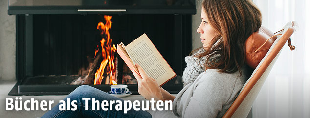 Frau liest vor offenem Kamin