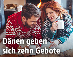 Ein Paar liegt auf einer Decke vor einem Lagerfeuer