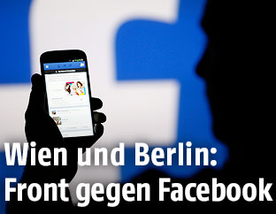 Hand hält Smartphone vor Facebook-Logo