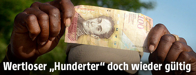 Mann zeigt eine 100-Bolivar Banknote