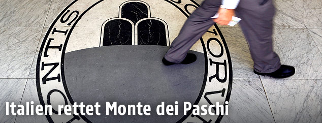 Ein Mann geht über ein Logo der Bank Monte dei Paschi