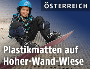 Mädchen sitzt auf einer Matte auf der Hohen-Wand-Wiese