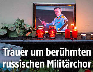 Kerzen und Blumen um ein Bild des Dirigenten des abgestürzten russischen Militärchors