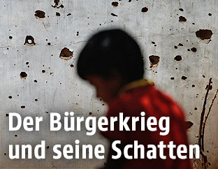 Kind vor einer durchlöcherten Mauer