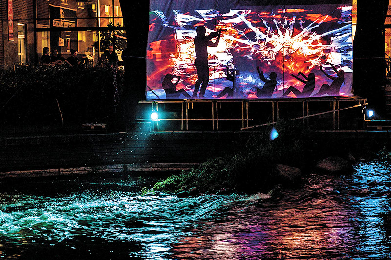 Projektion auf einer Leinwand neben einem Fluss
