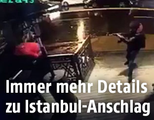 Ein Standbild einer Überwachungskamera zeigt einen Maskierten mit Waffe