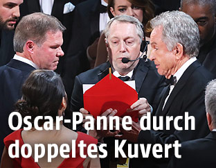 Warren Beatty und Mitarbeiter mit dem Kuvert auf der Bühne
