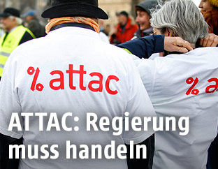 Personen tragen T-Shirts mit Attac-Logo