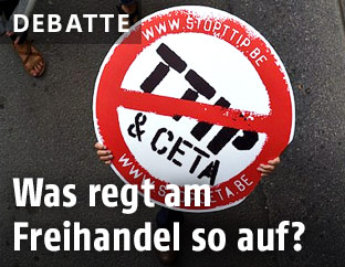 Demonstrant hält ein Schild mit durchgestrichenem Schriftzug TTIP & CETA in die Höhe