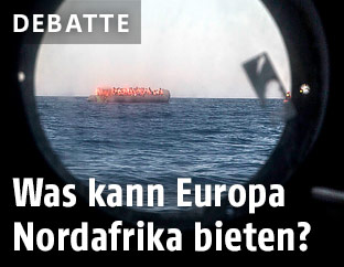 Fl&uuml;chtlinge auf einem Schlauchboot durch eine Schiffsluke gesehen