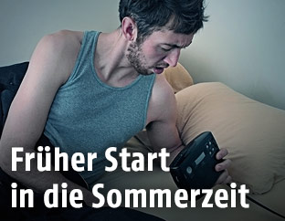 Ein Mann schaut auf seinen Wecker