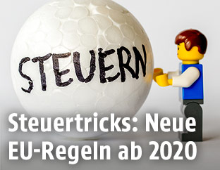 Legomännchen mit einer Styroporkugel auf der "Steuern" draufsteht