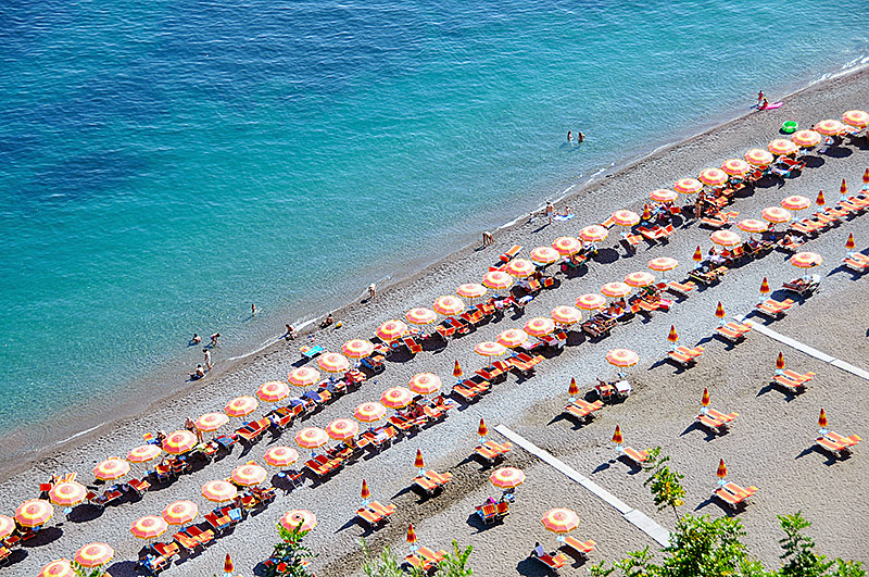 © Getty Images/Christian Schcolnik Touristen an einem italienischen Strand mit Sonnenschirmen und Sonnenliegen