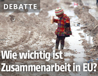 Kleines Kind steht im Schlamm eines Fl&uuml;chtlingscamps