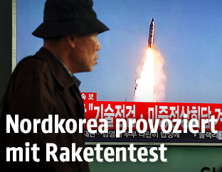 Menschen vor einem Fernseher der den Raketenstart zeigt