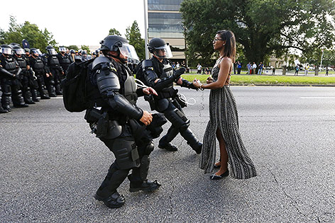 Archivbild zeigt eine junge Frau im Sommerkleid vor zwei Polizisten