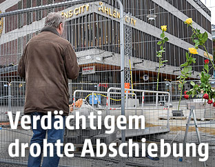 Ein Mann steht am Anschlagsort in Stockholm vor einer Absperrung mit Blumen