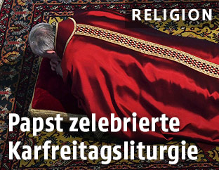 Papst Franziskus liegt mit dem Bauch auf dem Boden und betet