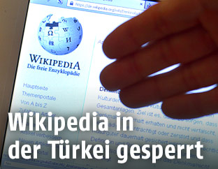 Hand deutet auf eine Wikipedia-Webseite