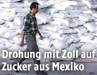Mexikanischer Arbeiter vor einem Berg von Zuckersäcken