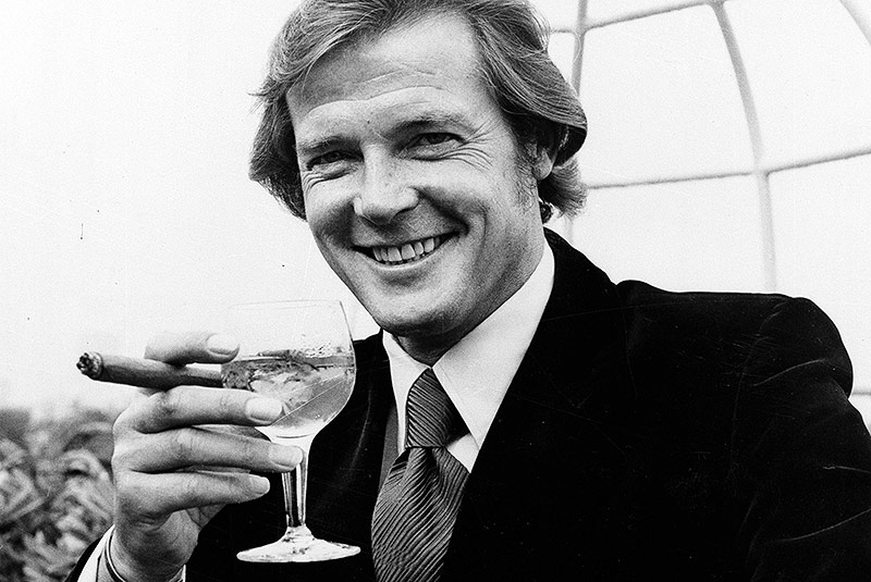 © AP/Bob Dear Archivbild des britischen Schauspielers Roger Moore mit einem Martini in der Hand aus dem Jahr 1971