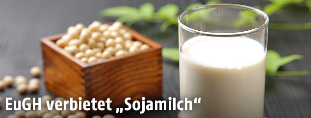 Ein Glas Sojamilch neben Sojabohnen