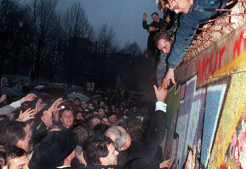 Helmut Kohl schüttelt die Hand eines Bürgers der über die Berliner Mauer geklettert ist